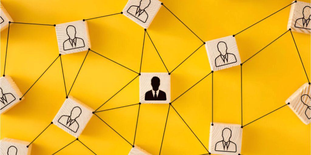 A top-down view of wooden blocks with black human silhouettes connected by black lines on a bright yellow background.